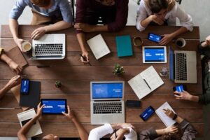 Overhead view of a diverse team in a business meeting using laptops and tablets.